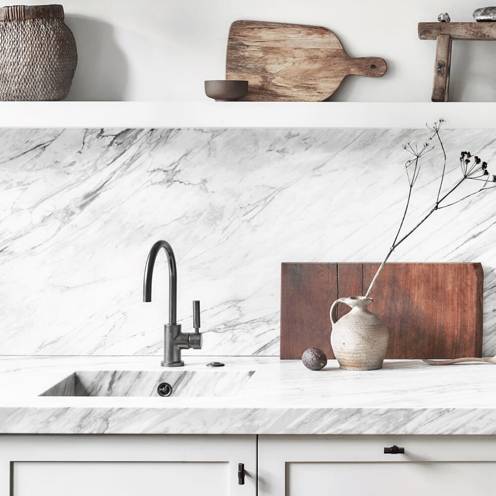 Elegant kitchen setup featuring marble benchtop and backsplash, matte black faucet, and rustic décor – ideal for modern Adelaide homes and kitchen tile inspiration.
