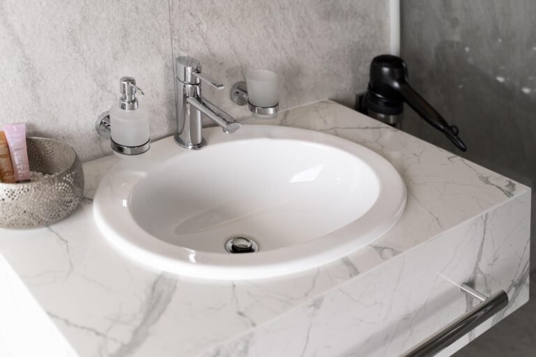 Compact vanity with round basin and modern fittings set against grey and marble textures in an Australian interior.