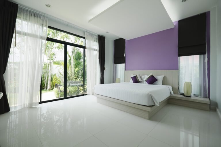 Contemporary Australian bedroom featuring glossy white tiles, sliding glass doors, and bold accent wall